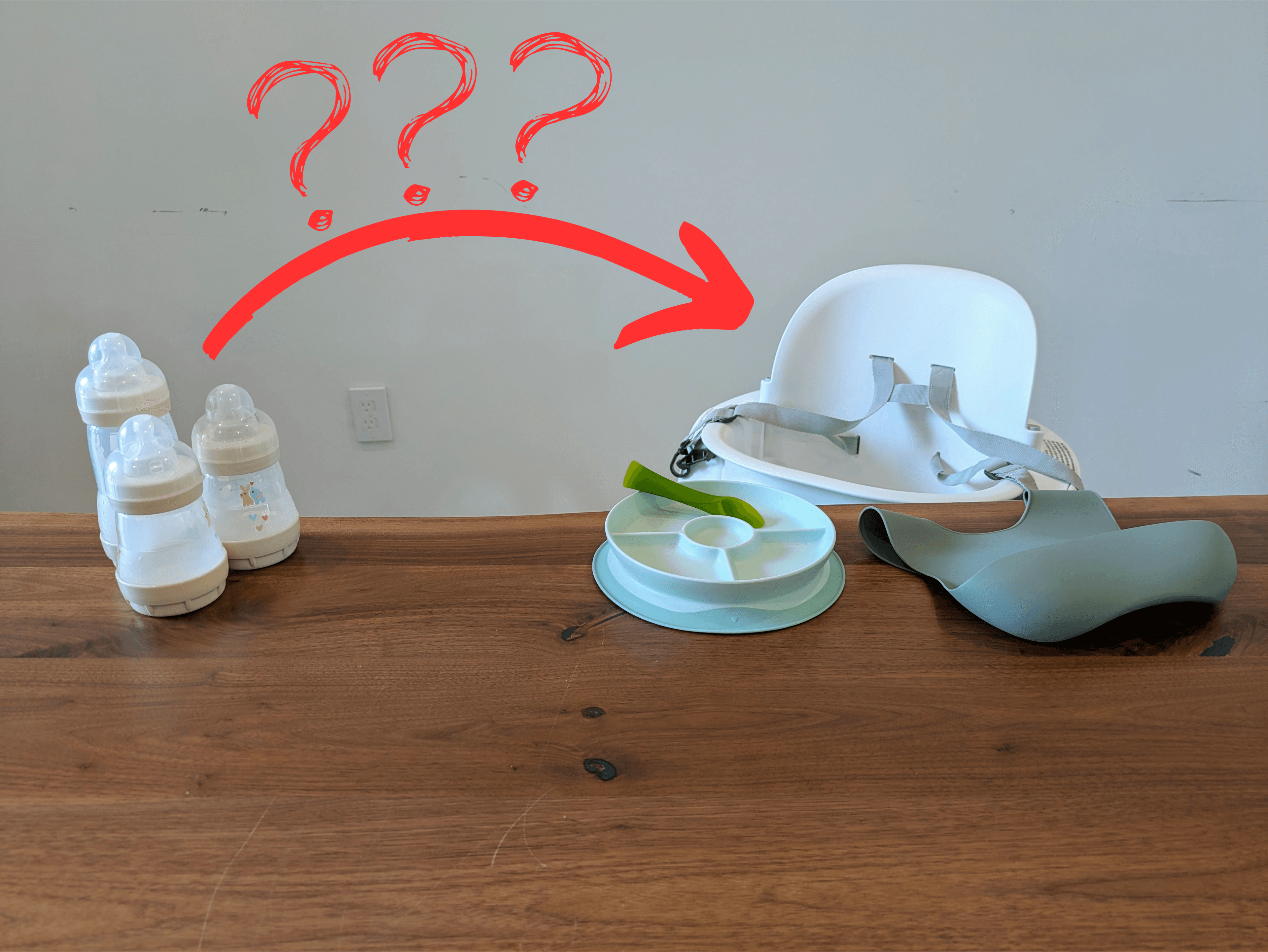 A photograph of a wooden table with bottles on the left and a baby plate, spoon, and bib on the right